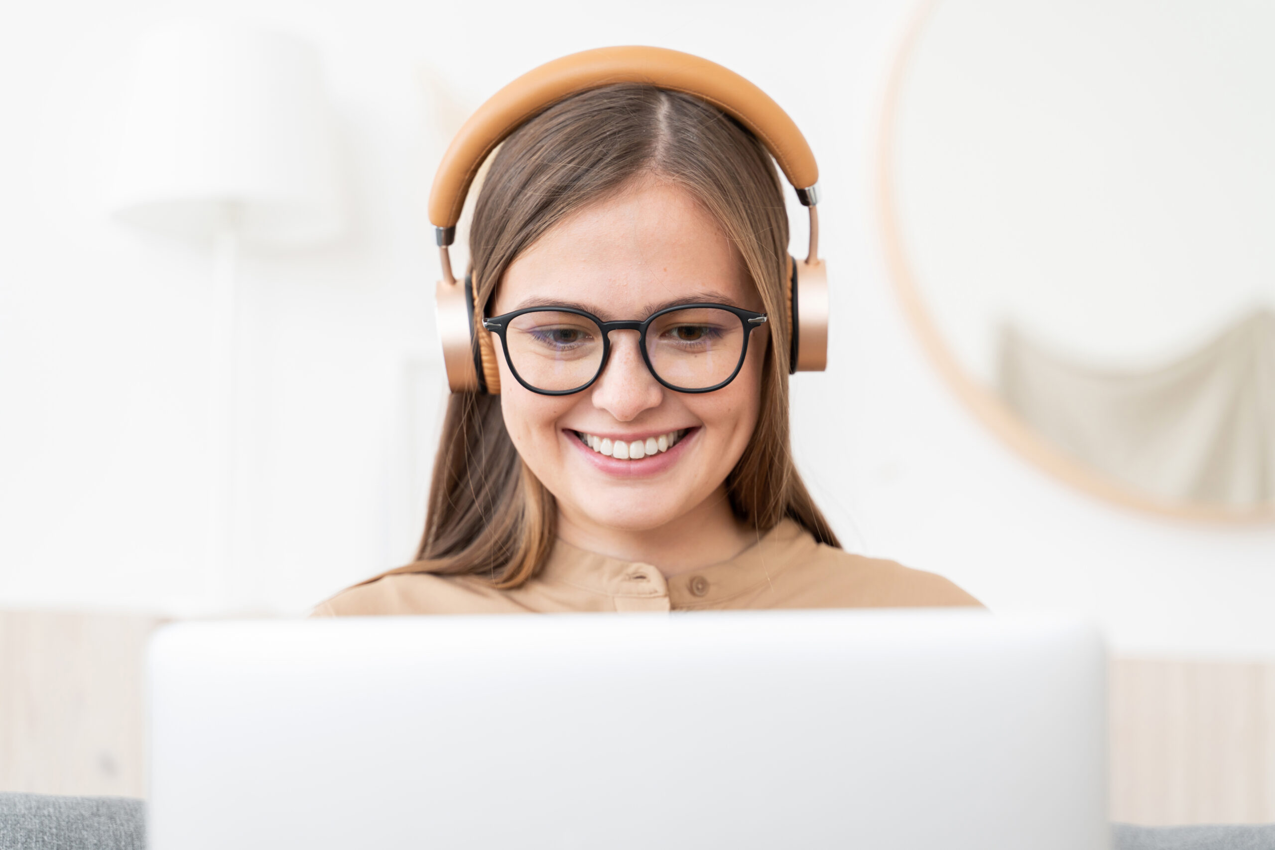 Laughing freelance girl spending time at home, working on laptop, listening to conference call